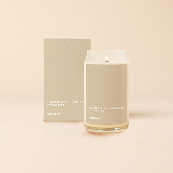 A 16 oz. candle with a beige colored decal that says, "MANIFEST &CHILL/SMELLS LIKE POSSIBILITIES." Scent is Bergamot.