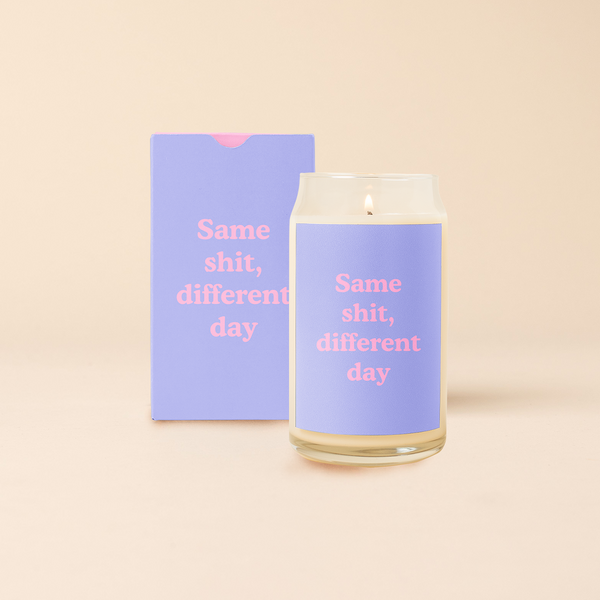 16 oz candle can glass with lavender decal and text that reads "Same shit, different day" in pink font. Lavender box with same design sits behind candle.
