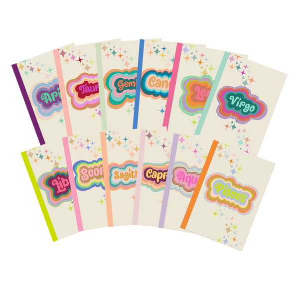 A collection of multicolored Astrological sign notebooks with a cream colored background and simple stars printed diagonally across the cover from the upper left corner, going down to the lower right corner.