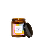 Amber glass candle jar with sticker on front with multi-color wavy design and text that reads "PRETTY & AWESOME" in purple font in a white square.