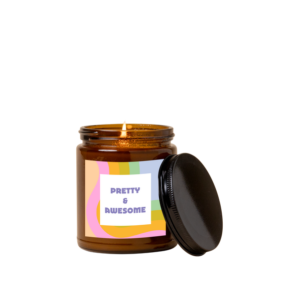 Amber glass candle jar with sticker on front with multi-color wavy design and text that reads "PRETTY & AWESOME" in purple font in a white square.