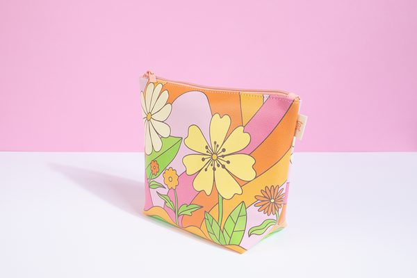 A groovy inspired designed pouch with rainbow arches, curvy lines, and differently designed flowers. Pouch is in pinks, greens, and oranges.
