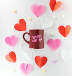 Sangria diner mug with the words "I fucking love you" on it. The mug is surrounded by pink, red, and white paper hearts, as well as candy conversation hearts.
