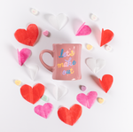 Pink ceramic diner mug with colorful cursive let's make out print with paper hearts and candy hearts