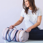 Girl next to darling duffel bag with stripes
