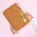 girls hand pulling laptop out of brown vegan leather laptop sleeve trimmed with fun floral print at the top with peach zipper