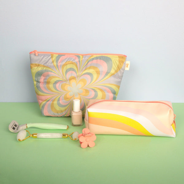 Light blue background with medium puffy kaleidoscope floral pattern tweedle dee and a pastel rainbow wave jitterbug on a green surface, along with misc items.