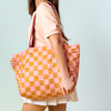 Tote bag with pink and orange checkered pattern; puffy texture and plum colored shoulder straps.