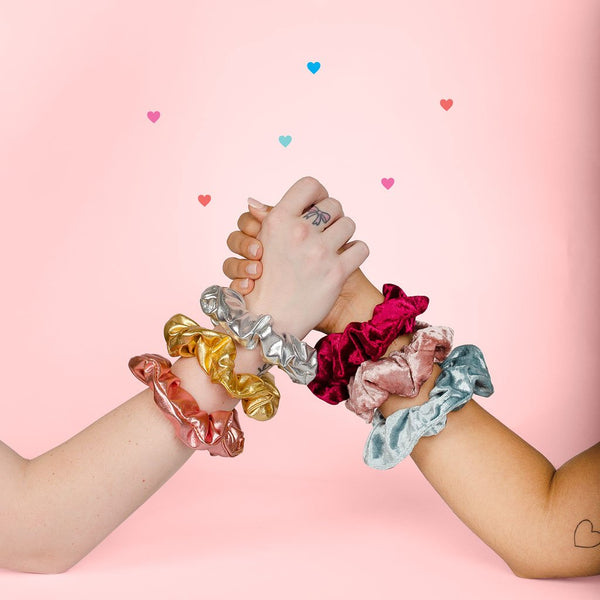 Girls arm wrestling with cute scrunchies on the wrists and tiny heart decal.