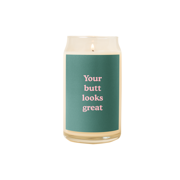 A 16 oz. candle with a green decal on it with the phrase "Your butt looks great" printed on.