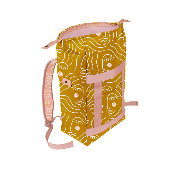 A mustard yellow backpack with an abstract female face design in white. Bag has pink straps and a front pocket. 