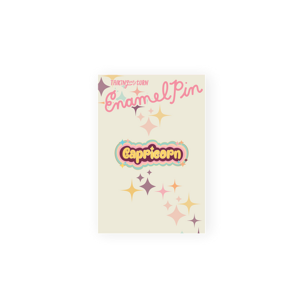 A Capricorn Enamel Pin in yellow lettering with a dark mauve background. Perimeter lining of pin is mint, pastel orange, pastel pink, and lilac.