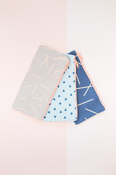 three different canvas pouches. one gray canvas with pixie sticks, one beach-washed denim with triangles, one navy with pixie sticks -- Beachwash Denim- Triangles