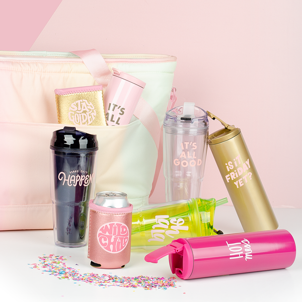 A pastel gradient cooler bag with a variety of beverage items tucked in the pocket and surrounding the bag. Confetti is sprinkled from a stainless steel tumbler. 