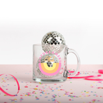 A image of the glass mug with the day dreamers club logo printed on front in yellow and pink colors, and with confetti and small disco balls decorating the mug.