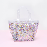 A small confetti tote sits on a pink surface. 
