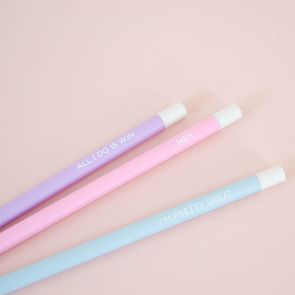 3 pastel colored pencils engraved with inspiring quotes laying on a pink surface