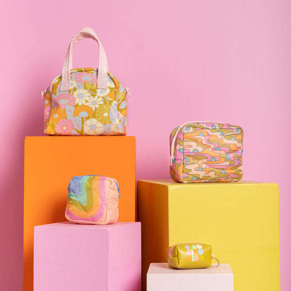 A few of the delightful bags/pouches on colored blocks and a pink background.