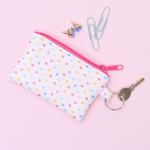 A cute coin purse key ring in blush pink with rainbow hearts pattern and a coral zipper.