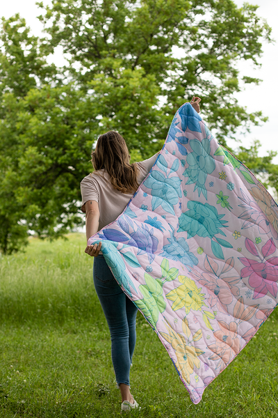 Multicolored floral quilted puffy blanket being carried by a person running outside.