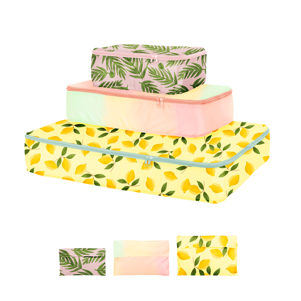 A small, medium, and large sized packing cube. Small cube is a leafy design with a light pink background, middle is a pastel ombre color, and bottom is a lemon design with a light yellow background and green lemon leaves attached to the lemons.