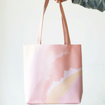 Girl's hand holding a cute tote bag in pink and peach cloud pattern.