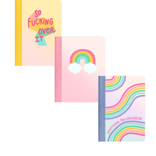 A plain background with 3 mini notebooks. The first one says "so fucking over it" the second is a rainbow with clouds and the third has rainbow paths and "emotional rollercoaster" written in pink scripts. 