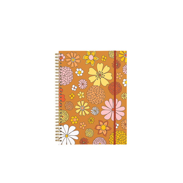 wire bound notebook with floral print on top of brown background with rust elastic closure