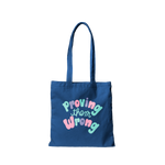 Navy canvas tote bag that says Proving Them Wrong in colorful lettering.