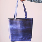 Girl's hand holding a cute tote bag in Indigo navy gradient pattern.