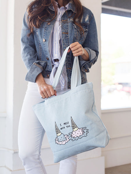 Brunette girl in denim jacket holding a denim tote bag with i melt with you double ice cream cones print.