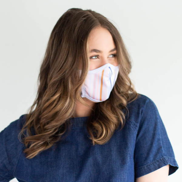 A brunette wears a lightly striped face masks and a jean shirt. 
