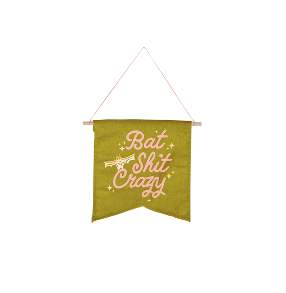 Olive green medium canvas wall flower with light pink lettering saying "bat shit crazy" with ombre yellow to white bat and star sparkles.