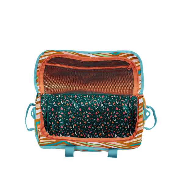 Inside of wildstipes traveler. It is a dark emerald green with multicolored terrazzo specs. Also has an orange mesh zipper pocket on the top of the inside of the bag.